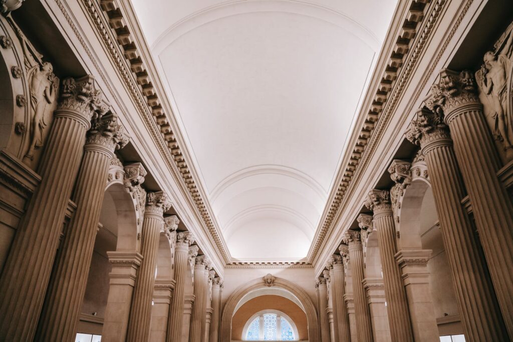 Interior of grand classic palace passage with majestic stone colonnade beneath arched white ceiling and ornamental stucco works